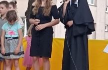 Dzieczynka w stroju zakonnicy oraz grupka dzieci podczas przedstawienia